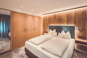上施陶芬Hotel Alpenkönig的卧室配有一张白色大床和木墙