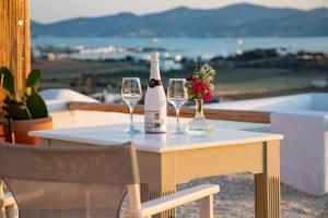 阿吉亚艾里尼帕罗Anthemion Paros - Villas & Suites的一张桌子,上面放有两瓶和两杯葡萄酒