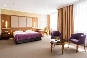 阿拉木图Reikartz Sky Almaty的酒店客房带一张床、一张桌子和椅子