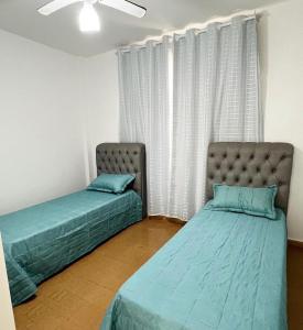 瓜拉派瑞Ap401 Praia do morro的两张床位于带窗户的房间内
