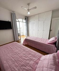 瓜拉派瑞Ap401 Praia do morro的一间卧室配有两张床和一台平面电视