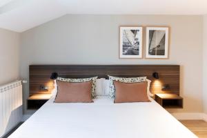 苏安塞斯Apartamentos Plaza Center的卧室配有一张带三个枕头的大型白色床