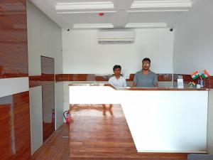 孟买Hotel Palms Residency, Chembur Mumbai的两个人站在房间里柜台