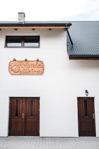 HrčavaHrčavská Mlékárna的两扇门的白色建筑的侧面标志