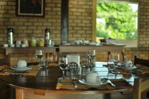 沙帕达-杜斯吉马朗伊斯POUSADA PEQUIZEIRO的木桌,带玻璃杯和盘子及酒杯