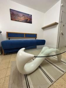 Qiryat H̱ayyimdgania lux的一张带白色椅子和蓝色沙发的玻璃桌