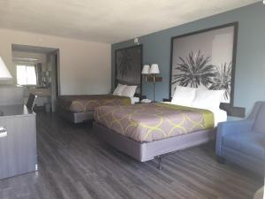 达尼亚滩Super 8 Motel by Wyndham near Fort Lauderdale Arpt的酒店客房,配有两张床和椅子