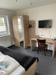WirdumHotel Zum Großen Krug的一间卧室配有书桌、一张床和一台电视。