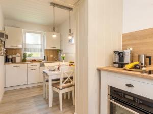 青斯特Ostseeklang的厨房配有白色橱柜和桌椅