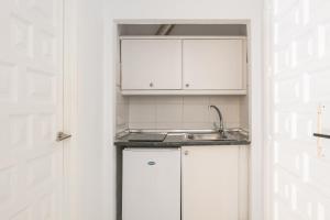 马罗Apartamentos Playamaro的厨房配有白色橱柜和水槽