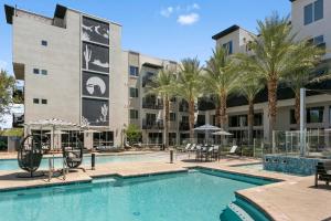 斯科茨Premium One and Two Bedroom Apartments at Slate Scottsdale in Phoenix Arizona的大楼前的带桌椅的游泳池