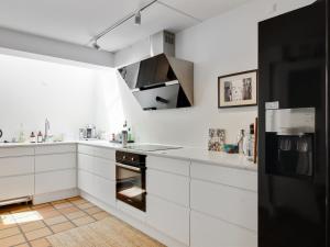 布洛克胡斯Apartment Virpi - 1km from the sea in NW Jutland by Interhome的厨房配有白色橱柜和黑色冰箱。