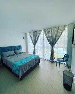 伊瓦格FINCA HOTEL EL ENSUEÑO的一间卧室配有一张床、一把椅子和窗户。