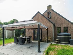 EwijkHoliday Home Forest Cottage Ewijk incl- hot tub by Interhome的一个带遮阳伞、桌子和烧烤架的庭院
