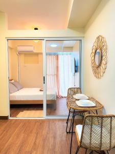 马尼拉1BR Prisma Residences DMCI Stylish Condo的配有一张床和一张桌子及椅子的房间