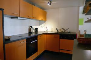 La Chaux-du-MilieuDrosera cabane et roulotte的厨房配有橙色橱柜和黑色洗碗机
