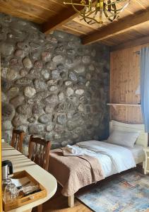 卡兹贝吉Inn Harmony的一间卧室设有石墙、一张床和一张桌子
