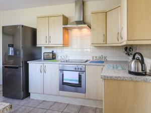 奥尔弗里顿Hideaway的厨房配有白色橱柜和不锈钢冰箱