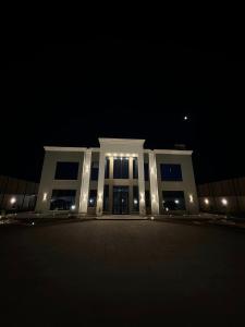 Al RamaThe Mansion villa的一座白色的大建筑,晚上有灯光