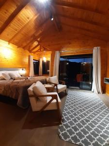 圣若阿金Pousada Recanto da Cascata - Cabana Platano的一间卧室配有一张床、一张沙发和椅子
