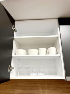 比雷埃夫斯Moschato New Home 3 vipgreece的白色的橱柜,上面有杯子和眼镜
