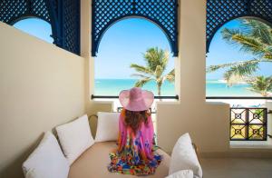 拉斯阿尔卡麦Hilton Ras Al Khaimah Beach Resort的坐在桌子上看着大海的小女孩