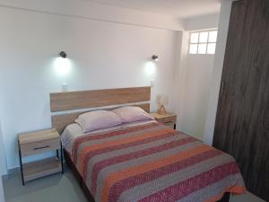 库斯科II - Zaguan Aparta Hotel Cusco的一间卧室配有带条纹毯子的床和2个床头柜