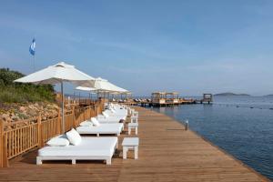 博德鲁姆Susona Bodrum, LXR Hotels & Resorts的码头上一排白色躺椅,上面有水