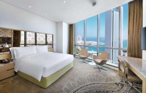 阿布扎比Conrad Abu Dhabi Etihad Towers的一间卧室配有一张床、一张书桌和一个大窗户