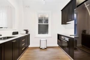 悉尼Sydney CBD Waterview apartment56的厨房配有黑色橱柜和窗户。