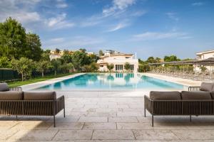 努马纳Borgopetra Resort的一个带两张沙发的大型游泳池和一个庭院