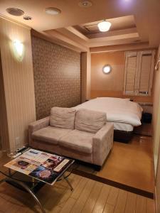 Koshigayaスタイリッシュ武里的一间卧室配有一张床、一张沙发和一张桌子