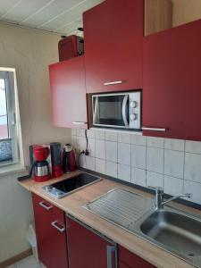 于克里茨Gästehaus Labahn的厨房配有红色橱柜、水槽和微波炉