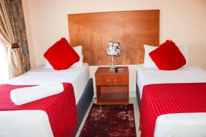 NqutuMeet Mekaar Resorts - Nquthu Hotel的宿舍间内的两张床,配有红色枕头