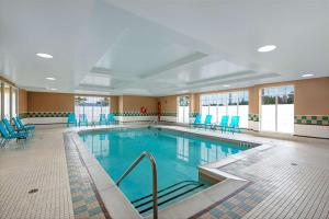 奥克维尔奥克维尔希尔顿惠庭套房酒店的一个带蓝色桌椅的大型游泳池