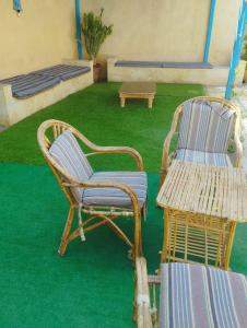 Tunisفيلا بيجو的绿草间里两把椅子和一张桌子