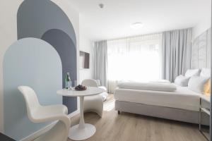 比勒费尔德zzzpace Smart-Hotel Bielefeld Zentrum的卧室配有1张床、1张桌子和1把椅子