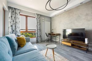 华沙Ochota City View Modern Apartment的客厅配有蓝色的沙发和平面电视。
