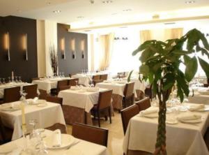 布尔戈斯hotel asador versus的一间设有白色桌子的餐厅,中间种植了植物