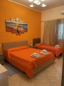 普拉Edeler House的卧室设有两张床铺和橙色墙壁