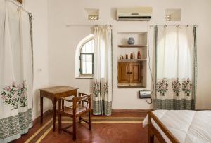 斋浦尔Kawa Guest House的卧室配有1张床、1张桌子和1把椅子