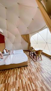 瓦迪拉姆Yellow Star Camp Wadi Rum的一间设有两张床的卧室和一张位于帐篷内的桌子