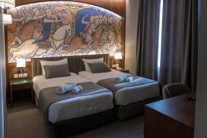 久姆里Orienta Hotel Gyumri的两张位于酒店客房的床,墙上挂着壁画
