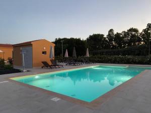 阿尔盖罗Maris Suite - Appartamento con vasca idromassaggio的庭院内的游泳池,配有椅子和遮阳伞