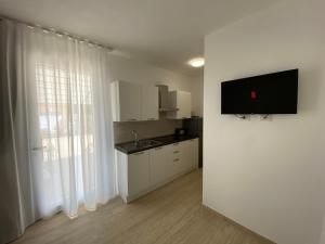 阿尔盖罗Maris Suite - Appartamento con vasca idromassaggio的厨房配有白色橱柜、水槽和窗户。