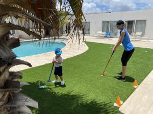棕榈滩创世纪公寓的一名女子和一个儿童在游泳池旁打高尔夫