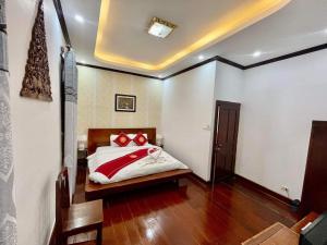 琅勃拉邦帕莎纳精品酒店的一间卧室配有一张带红色枕头的床