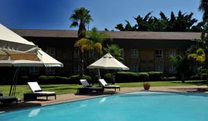 哈博罗内哈博罗内克里斯塔洛奇酒店的一座带椅子和遮阳伞的游泳池位于一座建筑旁边