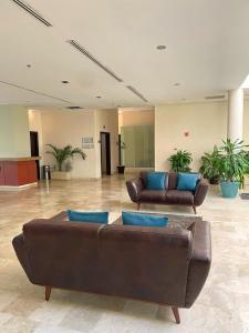 雷诺萨Altavista Hotel的大堂设有两张真皮沙发和蓝色枕头。