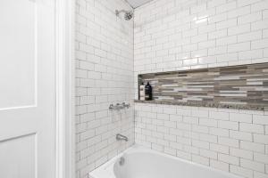 克拉克斯维尔The Loft At Madison Terrace - Private Unit的带浴缸的白色瓷砖浴室和窗户。